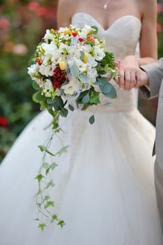 Bride holding wedding bouquet of colorful flowers and roses 