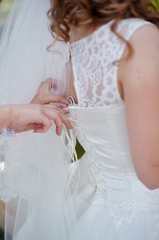 bridesmaids helps to bride dress in wedding morning.