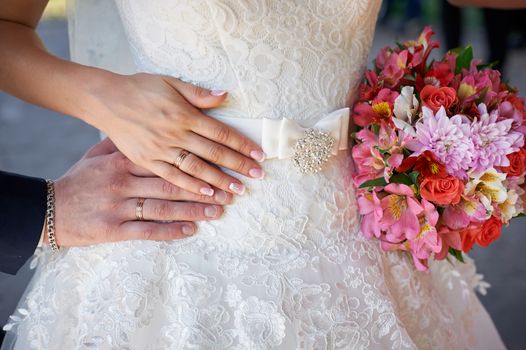 hands of the bride and groom with rings and wedding bouquet.