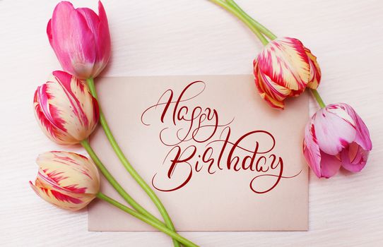 Bouquet of red tulips on white background with text Happy Birthday. Calligraphy lettering.