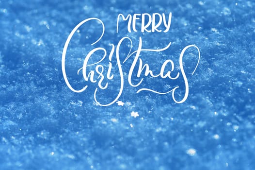 texture of snow in blue tones background with text Merry Christmas. Calligraphy and lettering.