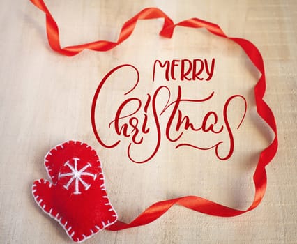 Christmas Background with Santa Claus red mitten and text Merry Christmas. Calligraphy lettering