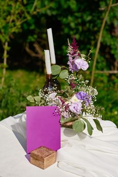 bouquet of flowers and two candles on the table for a wedding ceremony in the Park.