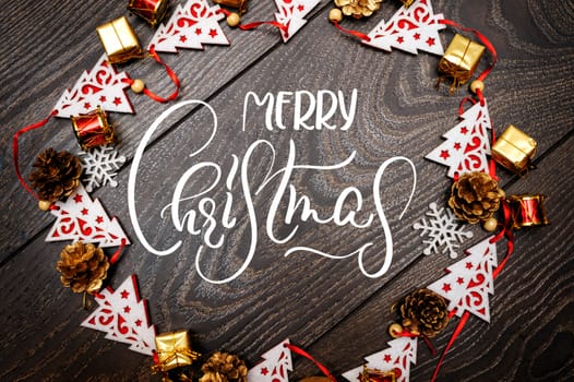 frame from toys fir trees on wooden background and text Merry Christmas. Calligraphy and lettering.