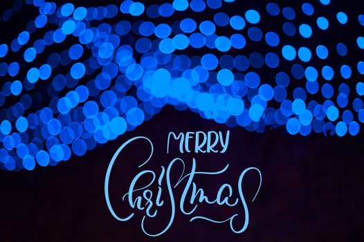 Blue blur Garland in Winter Park Christmas Decor with text Merry Christmas. Calligraphy and lettering.