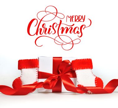 beautiful gift boxes with red ribbons and branch of tree and text Merry Christmas. Calligraphy lettering.