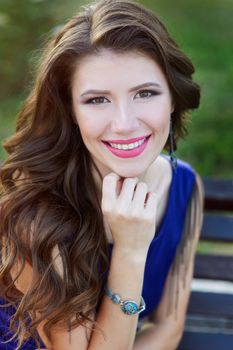 beautiful young woman sitting on a bench in the Park. hairstyle and make up