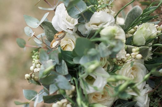 beautiful wedding rings on a bouquet of white roses.