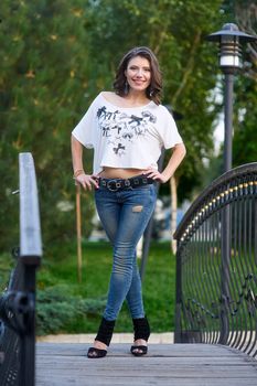 young woman in jeans and a t-shirt on a bridge in the Park.