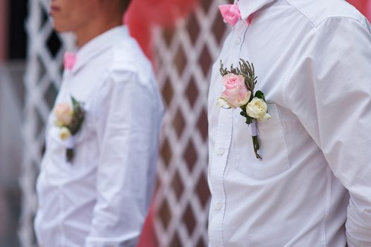 friends of the groom at the wedding ceremony with the buttonhole on the shirt.