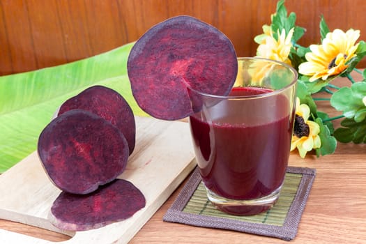 Fresh slices red beetroot and beetroot fruit juice in glass a wood background