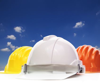 three of safety helmet construction protection on white against beautiful blue sky and white cloud with copy space 