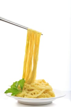 steel chopstick holding chinese yellow eggs noodle on white disk with green leaves of  celery ready to eating meal on white background 
