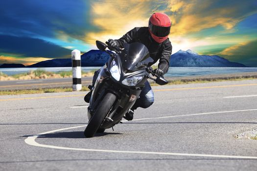young man riding motorcycle in asphalt road curve with rural and mountain background