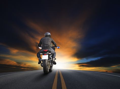 young man riding big bike motocycle on asphalt high way against beautiful dusky sky use for biker traveling and journey theme