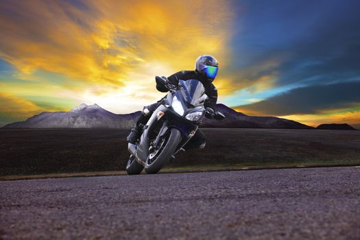 young man riding motorcycle in asphalt road curve with rural and mountain background 