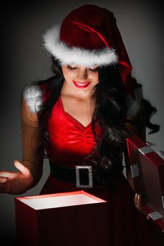 Woman in santa claus costume opening magic christmas gift