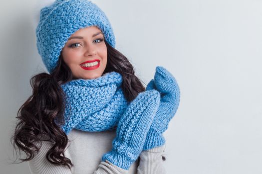 Smiling woman wearing blue winter hat, scarf and mittens
