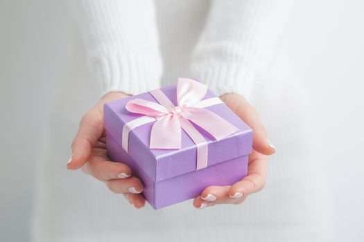 Woman holding small purple gift box in hands