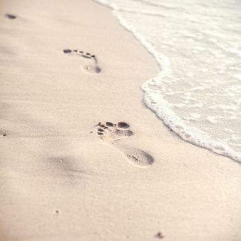 Soft focus and tone of footprints on the tropical beach sand with coast line. Journey  and leisure concept.
