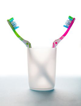 two toothbrushes in a glass on white background