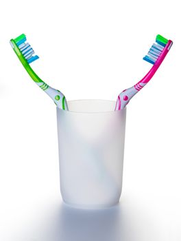 two toothbrushes in a glass on white background
