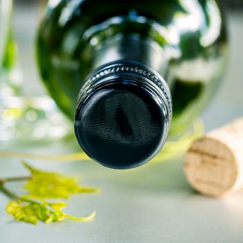 Close up wine Bottle with grape vine and wine cork on white table. Shallow depth of field . Dinning and Wining concept .