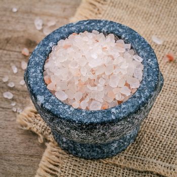 Himalayan pink salt in mortar on hemp sack background. Himalayan salt commonly used in cooking and for bath products such as bath salts