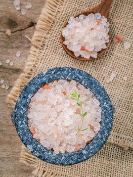 Himalayan pink salt in mortar with thyme on hemp sack background. Himalayan salt commonly used in cooking and for bath products such as bath salts