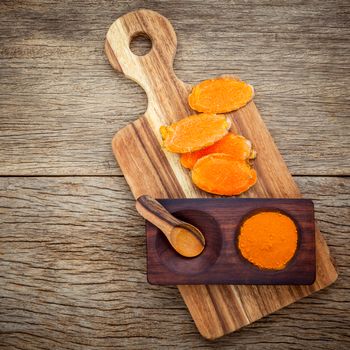 Alternative ingredients for skin care. Homemade scrub curcumin powder and curcumin roots with cutting board set up on old wooden background.