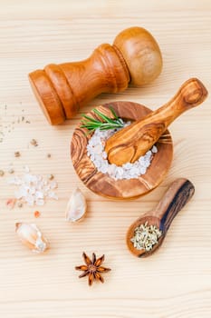 Close up Himalayan pink salt in wooden mortar and herbs garlic ,dried thyme, pepper ,fennel seed ,rosemary and star anise  on wooden background. Himalayan salt commonly used in cooking .