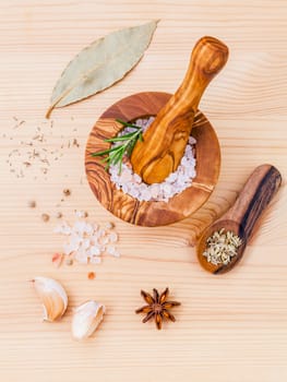 Close up Himalayan pink salt in wooden mortar and herbs garlic ,dried thyme, pepper ,fennel seed ,rosemary and star anise  on wooden background. Himalayan salt commonly used in cooking .
