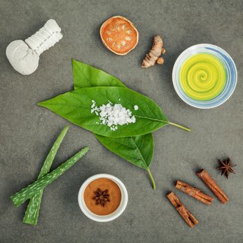 Avocados leaves with nature spa ingredients turmeric,herbal compress ball,dried indian bael ,cinnamon powder ,cinnamon sticks ,aromatic oil ,star anise,aloe vera and sea salt on concrete background.