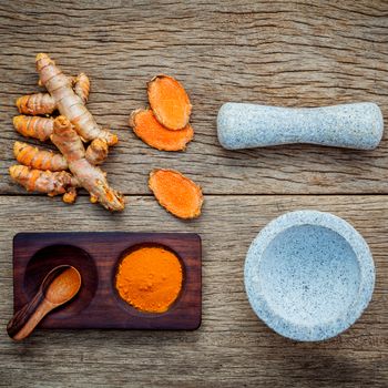 Alternative ingredients for skin care. Homemade scrub curcumin powder and curcumin roots with white mortar set up on old wooden background.