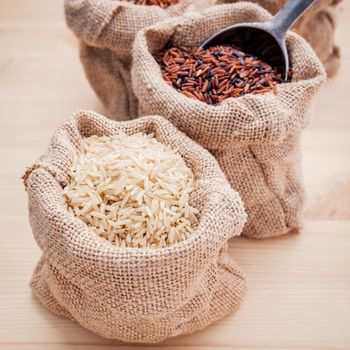 Mixed whole grain traditional thai rices best rices for healthy and super food in hemp sacks bag setup on wooden background.
