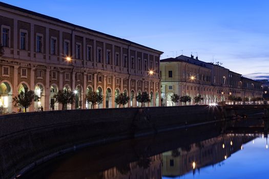 The river flowing through the city reflects the buildings at sunset