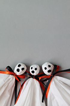 Halloween concept background : Three halloween ghosts DIY made from white tissue paper, black and orange ribbon on gray background