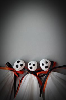 Halloween concept background : Three halloween ghosts DIY made from white tissue paper, black and orange ribbon on gray background