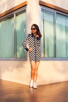portrait of beautiful young woman wearing sun glasses and short dress chick fashion style standing on home corner 
