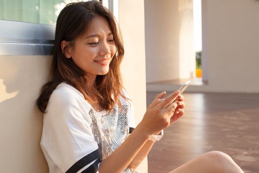 portrait of beautiful young and teen woman looking to mobile phone with smiling face in home outdoor use for chat talking and internet on line connecting technology