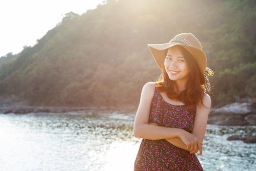 portrait of beautiful young woman wearing wide straw hat standing beside sea beach and toothy smiling face wtih happy emotion 