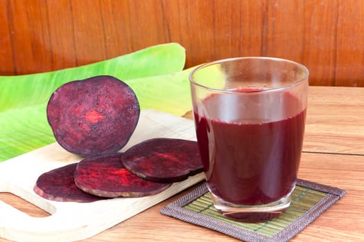 Fresh slices red beetroot and beetroot fruit juice in glass a wood background