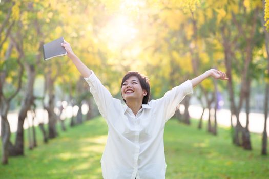 portrait of young asian woman and book in hand rising hand as victory with happiness face emotion use for people success in education and business 
