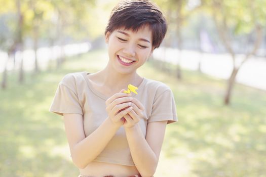young and beautiful woman laughing to little flowers in hand with happy face by shallow depth of field and pastel vintage color style