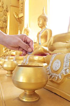 Give coin in alms bowl, a man put a Baht coin in a monk bowl for making merit or donation, buddhism Thai people donating money for temple, row of bowl