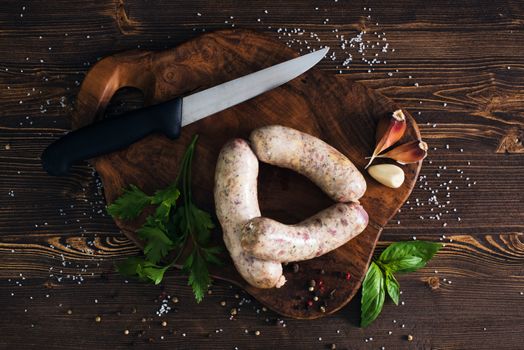 Raw sausages with garlic and parsley on the cutting board