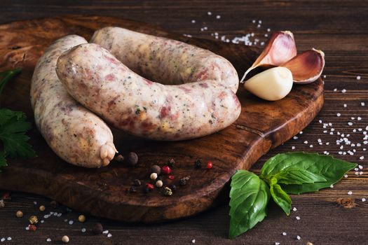 Raw sausages with garlic and parsley on the cutting board