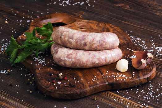 Raw sausages with garlic and parsley on the cutting board