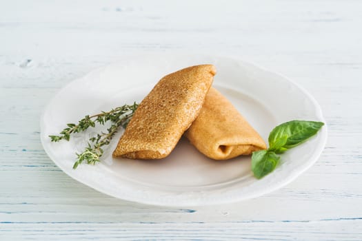 Stuffed pancakes on light wooden background