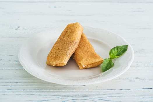 Stuffed pancakes on light wooden background